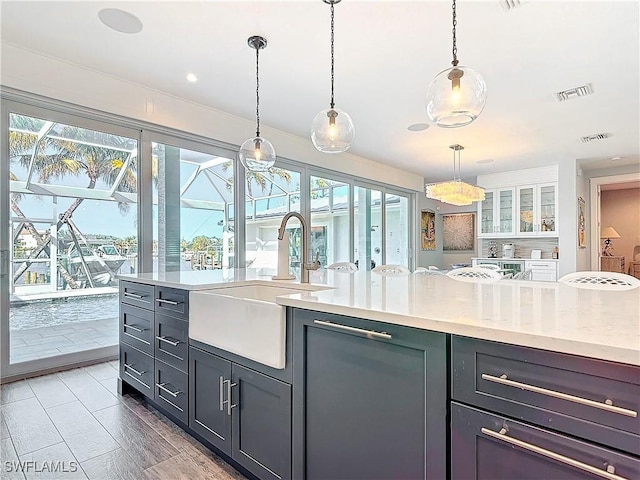 kitchen with decorative light fixtures, light stone countertops, and sink