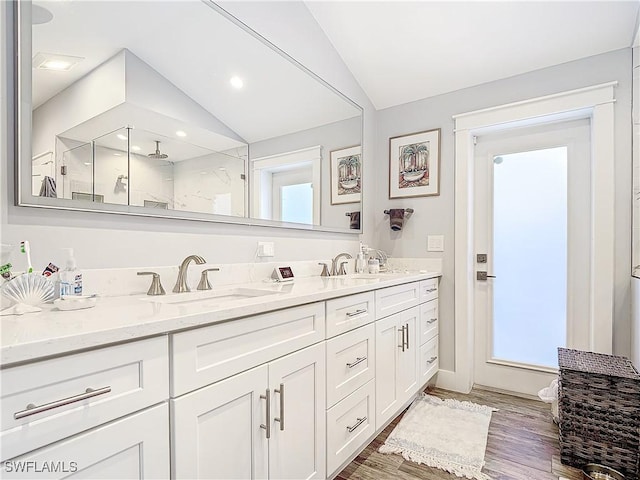 bathroom with vanity, hardwood / wood-style flooring, walk in shower, and lofted ceiling