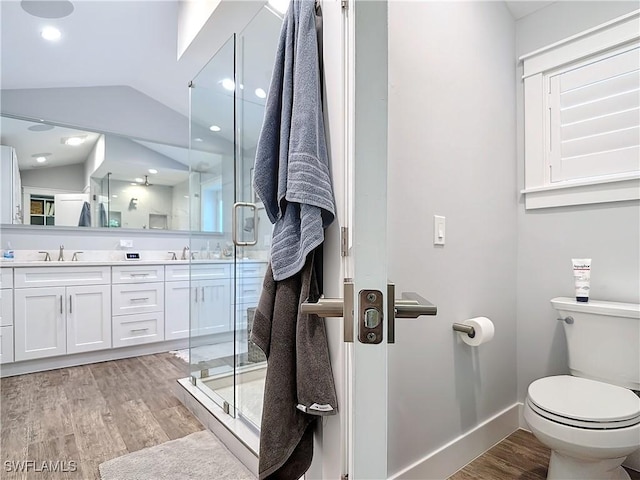 bathroom featuring vanity, hardwood / wood-style flooring, a shower with door, and lofted ceiling