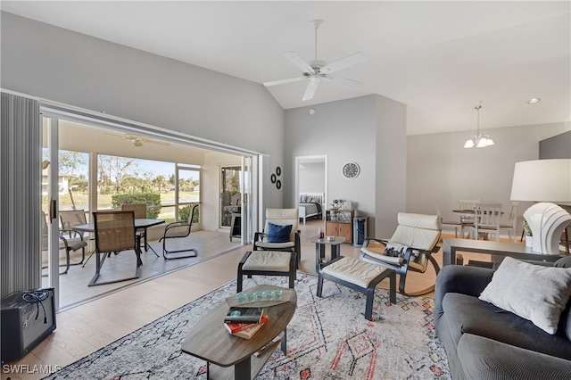 living area with vaulted ceiling, ceiling fan with notable chandelier, and light wood-type flooring