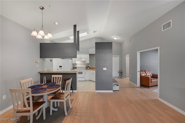 kitchen with kitchen peninsula, white appliances, a notable chandelier, white cabinetry, and lofted ceiling