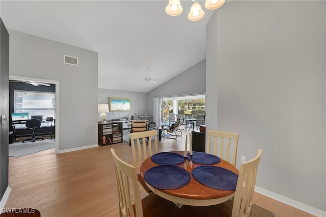 dining space with ceiling fan, light wood-type flooring, and vaulted ceiling