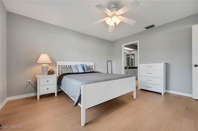 bedroom with ceiling fan, ensuite bathroom, and light hardwood / wood-style floors