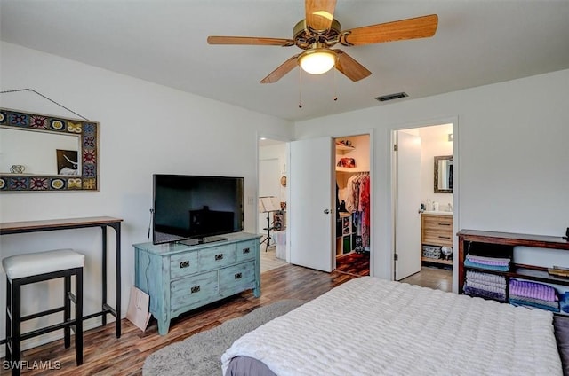 bedroom featuring a walk in closet, dark wood-type flooring, ceiling fan, and a closet