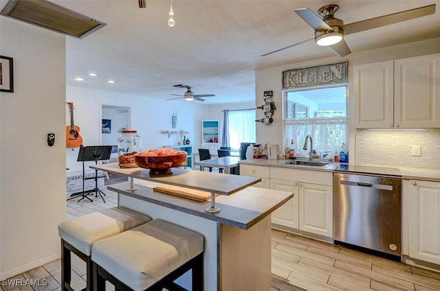 kitchen featuring sink, white cabinetry, dishwasher, and tasteful backsplash