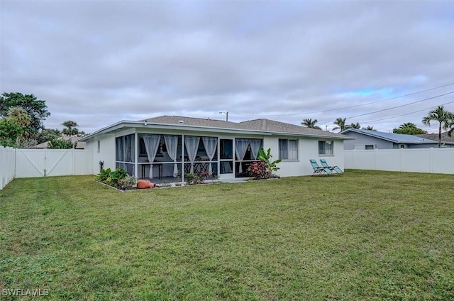 back of property with a sunroom and a lawn