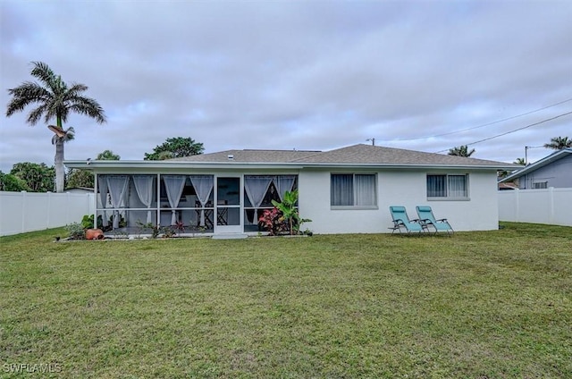 rear view of house featuring a yard and a sunroom