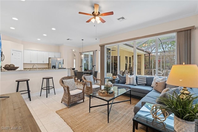 tiled living room featuring ceiling fan, ornamental molding, and sink