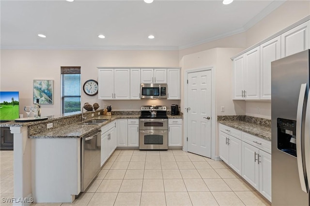 kitchen with kitchen peninsula, stainless steel appliances, white cabinetry, dark stone countertops, and sink