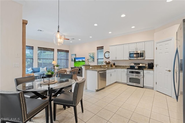 kitchen featuring white cabinetry, light stone counters, hanging light fixtures, and appliances with stainless steel finishes