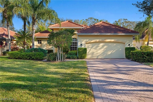 mediterranean / spanish house featuring a front yard, decorative driveway, an attached garage, and stucco siding