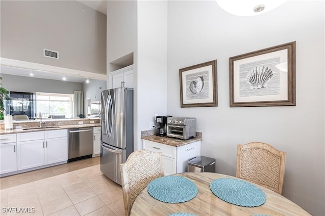 kitchen featuring white cabinetry, light stone counters, appliances with stainless steel finishes, and a sink