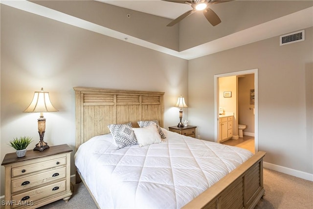 bedroom featuring visible vents, baseboards, light carpet, ensuite bath, and a ceiling fan