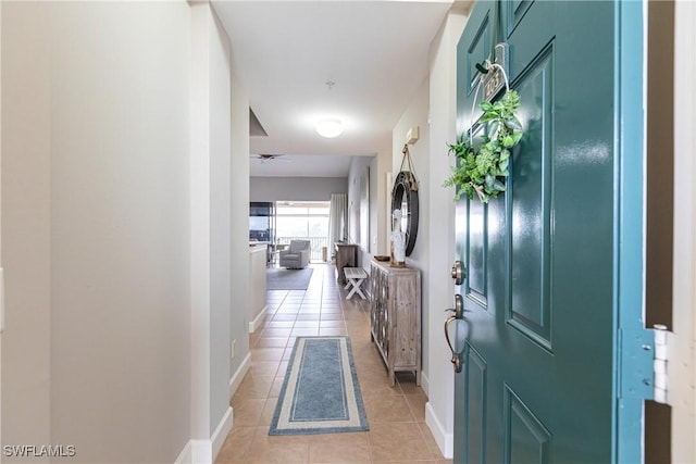 foyer entrance featuring ceiling fan, baseboards, and light tile patterned flooring