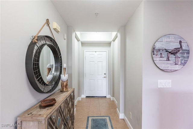 doorway with light tile patterned floors and baseboards