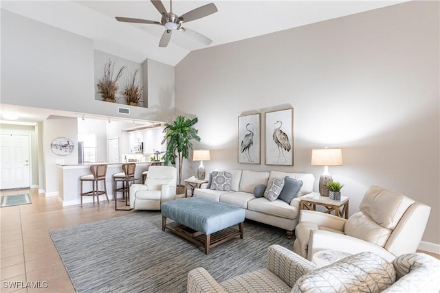 living area featuring ceiling fan, baseboards, high vaulted ceiling, and light tile patterned flooring