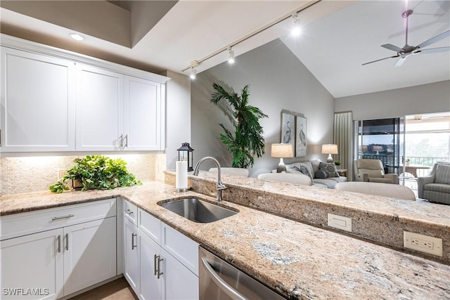 kitchen with light stone countertops, white cabinetry, a sink, dishwasher, and tasteful backsplash