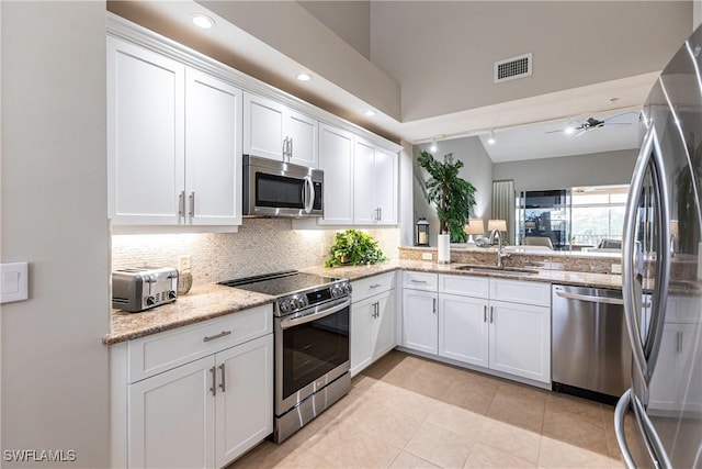 kitchen featuring visible vents, a sink, decorative backsplash, stainless steel appliances, and white cabinetry