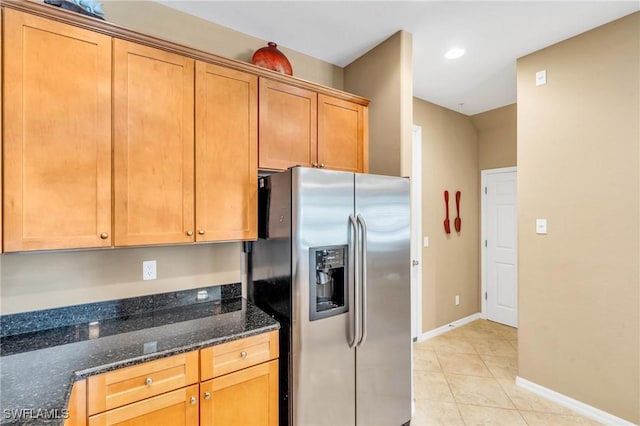 kitchen with stainless steel refrigerator with ice dispenser, dark stone counters, and light tile patterned floors