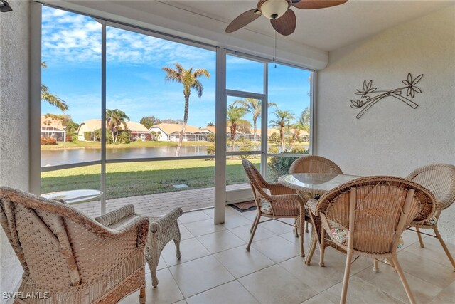 sunroom featuring a water view, ceiling fan, and a healthy amount of sunlight