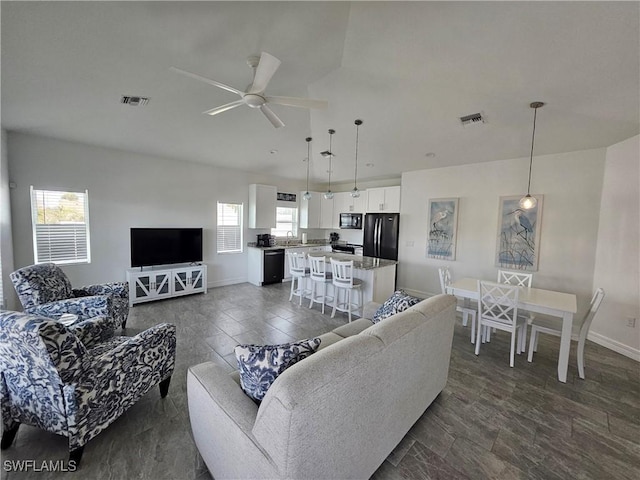 living room with ceiling fan, plenty of natural light, and sink