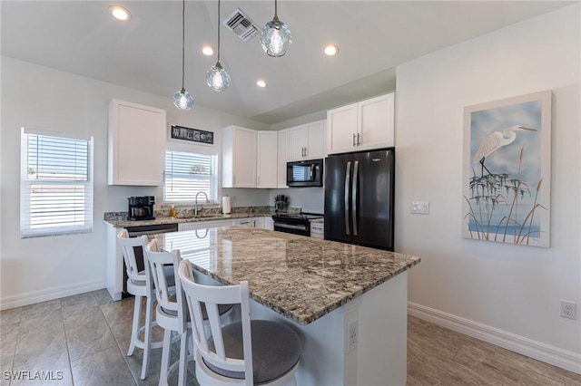 kitchen featuring dark stone countertops, a kitchen island, black appliances, sink, and white cabinets