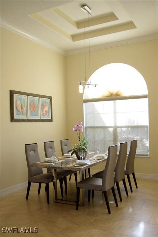 dining space with light tile patterned flooring, ornamental molding, and a tray ceiling