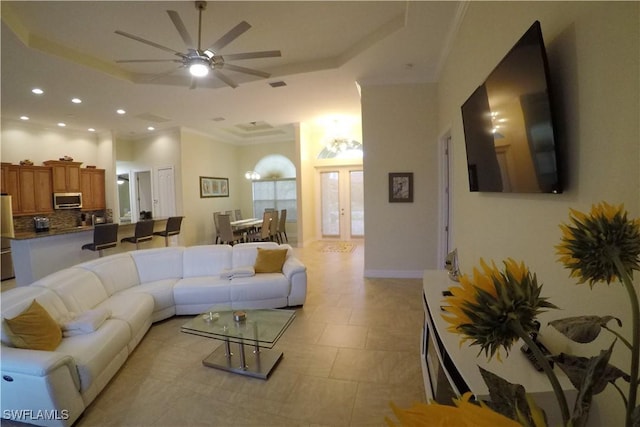 living room with ceiling fan, crown molding, and a tray ceiling