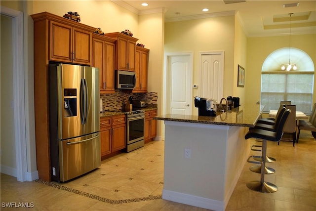 kitchen with a high ceiling, dark stone countertops, a chandelier, a breakfast bar area, and appliances with stainless steel finishes