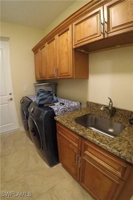 laundry area featuring light tile patterned flooring, cabinets, independent washer and dryer, and sink