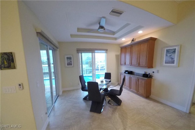 dining room with ceiling fan and a tray ceiling