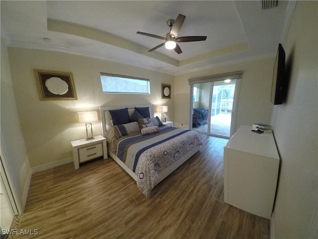 bedroom featuring ornamental molding, access to outside, a tray ceiling, ceiling fan, and hardwood / wood-style floors