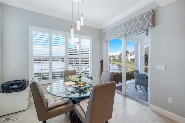 tiled dining area with a water view, a healthy amount of sunlight, and ornamental molding