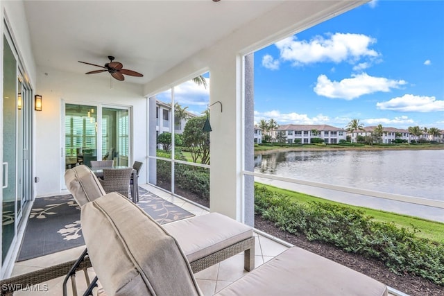 sunroom with ceiling fan and a water view