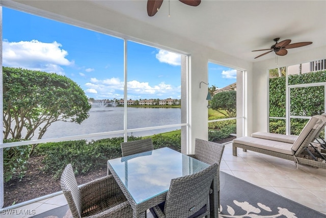 sunroom featuring ceiling fan and a water view