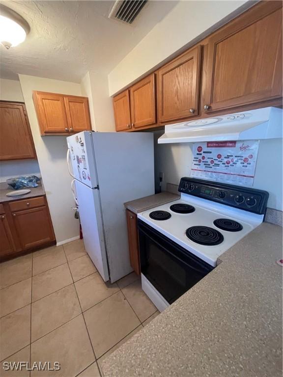 4861 Regal, Bonita Springs, FL 34134 - kitchen featuring light tile patterned flooring and white appliances