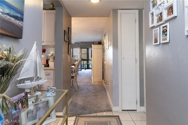 corridor with light carpet, baseboards, and light tile patterned flooring