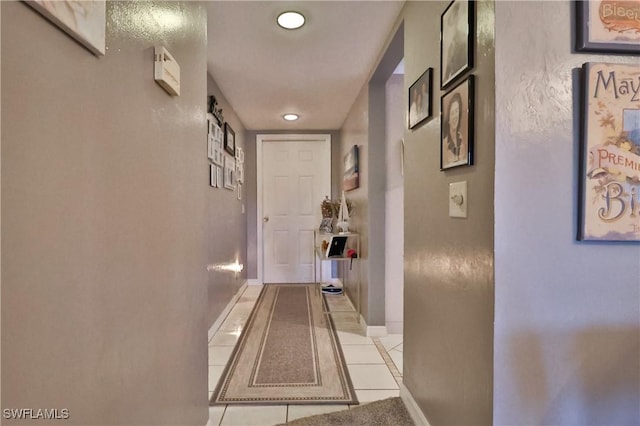 corridor with light tile patterned flooring and baseboards