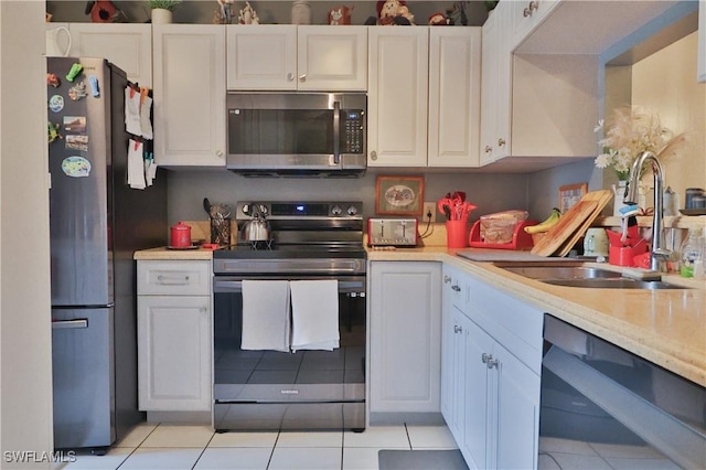 kitchen with light tile patterned flooring, white cabinetry, sink, and appliances with stainless steel finishes