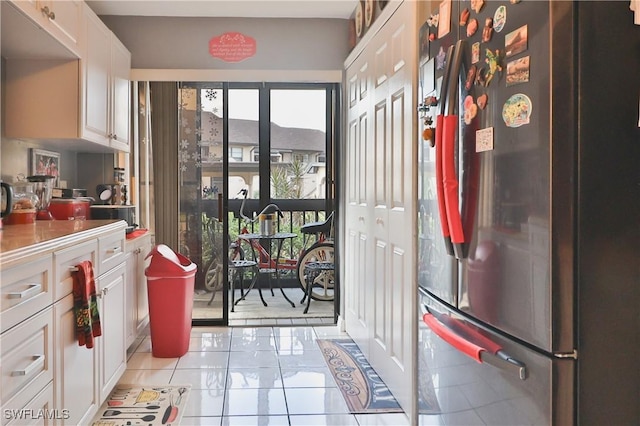 kitchen with light tile patterned floors, white cabinetry, and stainless steel refrigerator