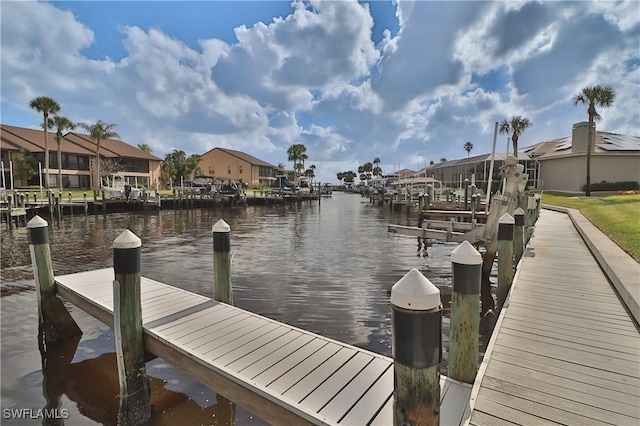 view of dock featuring a water view, boat lift, and a residential view