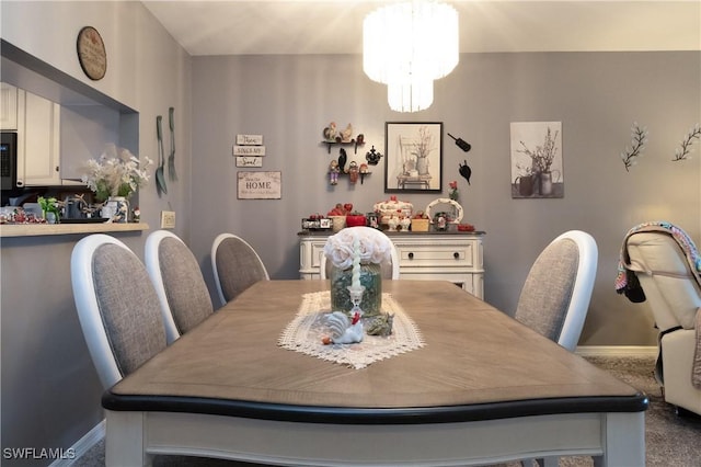 dining space featuring baseboards, a notable chandelier, and carpet flooring