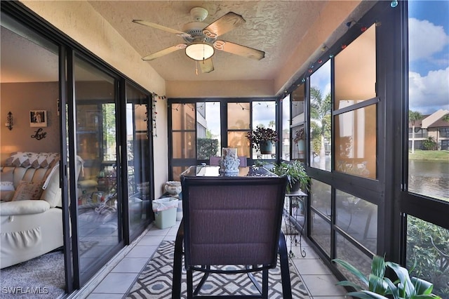 sunroom featuring plenty of natural light, ceiling fan, and a water view