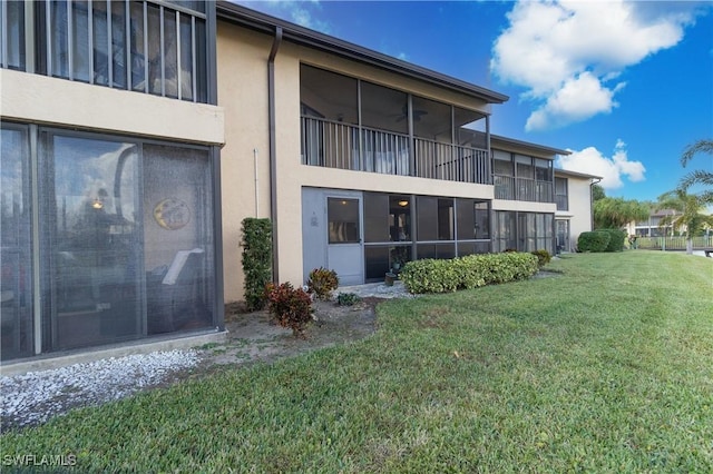 rear view of property featuring a yard and stucco siding