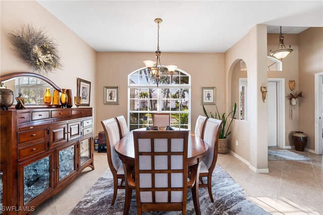 dining space featuring arched walkways, plenty of natural light, light tile patterned flooring, and baseboards