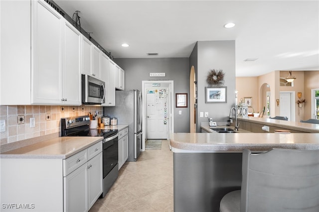 kitchen with a sink, visible vents, white cabinets, appliances with stainless steel finishes, and tasteful backsplash