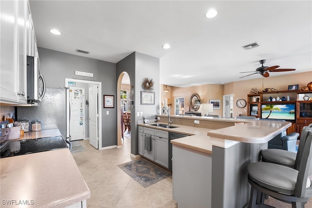 kitchen with a kitchen bar, visible vents, arched walkways, and stainless steel microwave