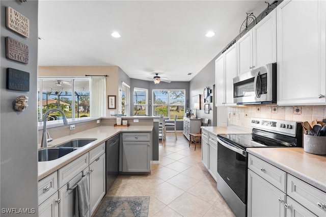 kitchen with light tile patterned flooring, stainless steel appliances, a sink, light countertops, and decorative backsplash