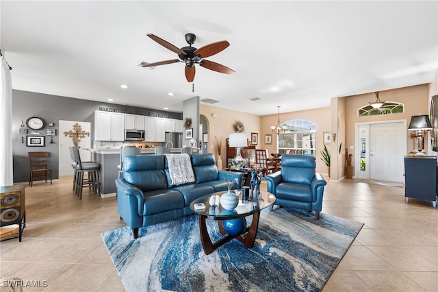 living area featuring ceiling fan with notable chandelier, arched walkways, recessed lighting, and light tile patterned floors