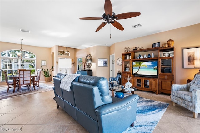 living area featuring ceiling fan with notable chandelier, visible vents, arched walkways, and light tile patterned flooring